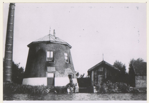 Poldermolen 'Nooitgedacht' stond in 1960 op een perceeltje weiland langs de Boonervliet, ongeveer in het midden van de kade die loopt van de Vlaardingse Vaart naar De Bommeer. Fotograaf: A.J. van Druten, Collectie Stadsarchief Vlaardingen, T653-046.