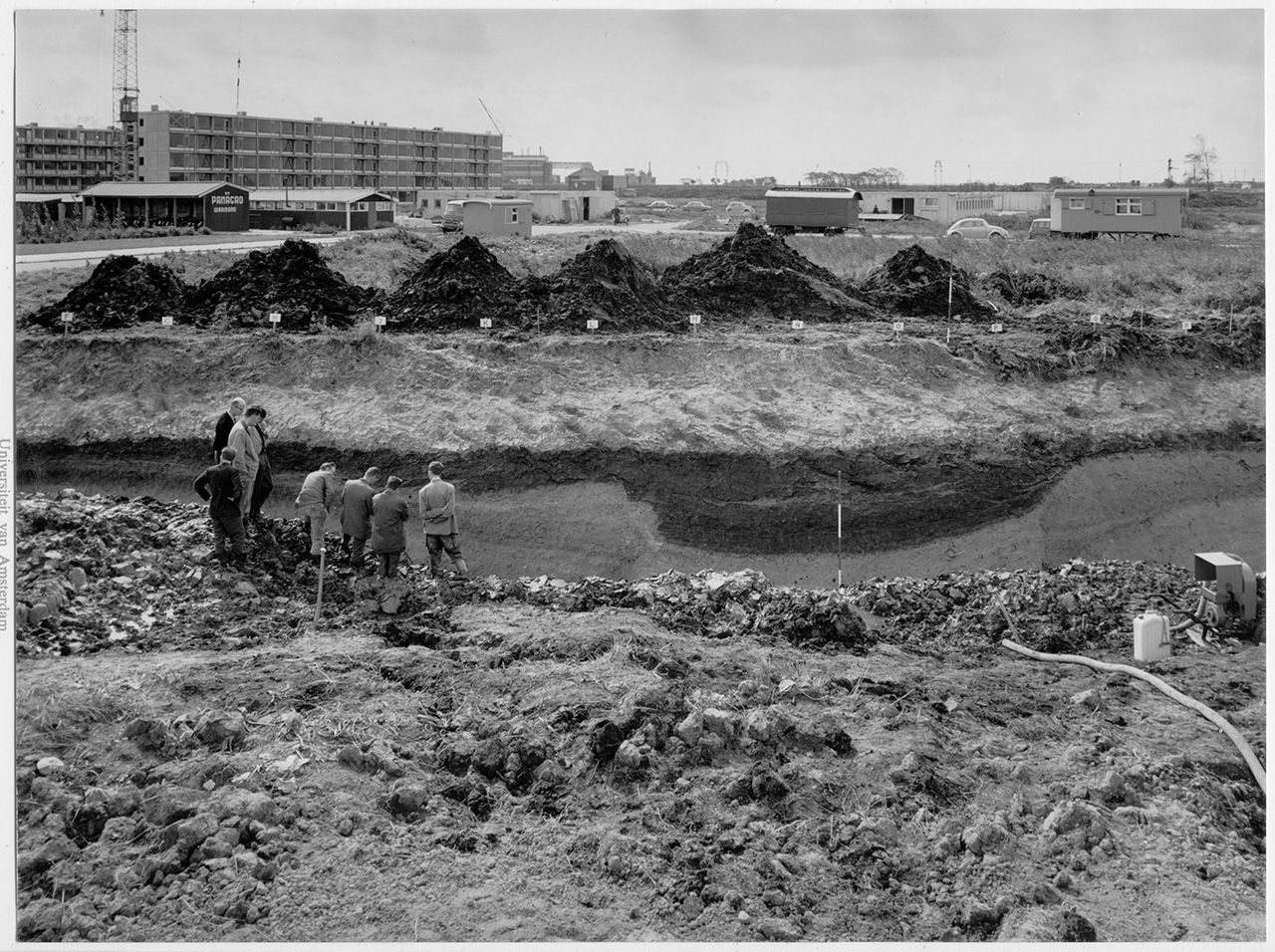 Wetenschappers bestuderen de archeologische sporen. Op de achtergrond de Westwijk in opbouw. Collectie Archeologie Vlaardingen, 07.003_id 187.