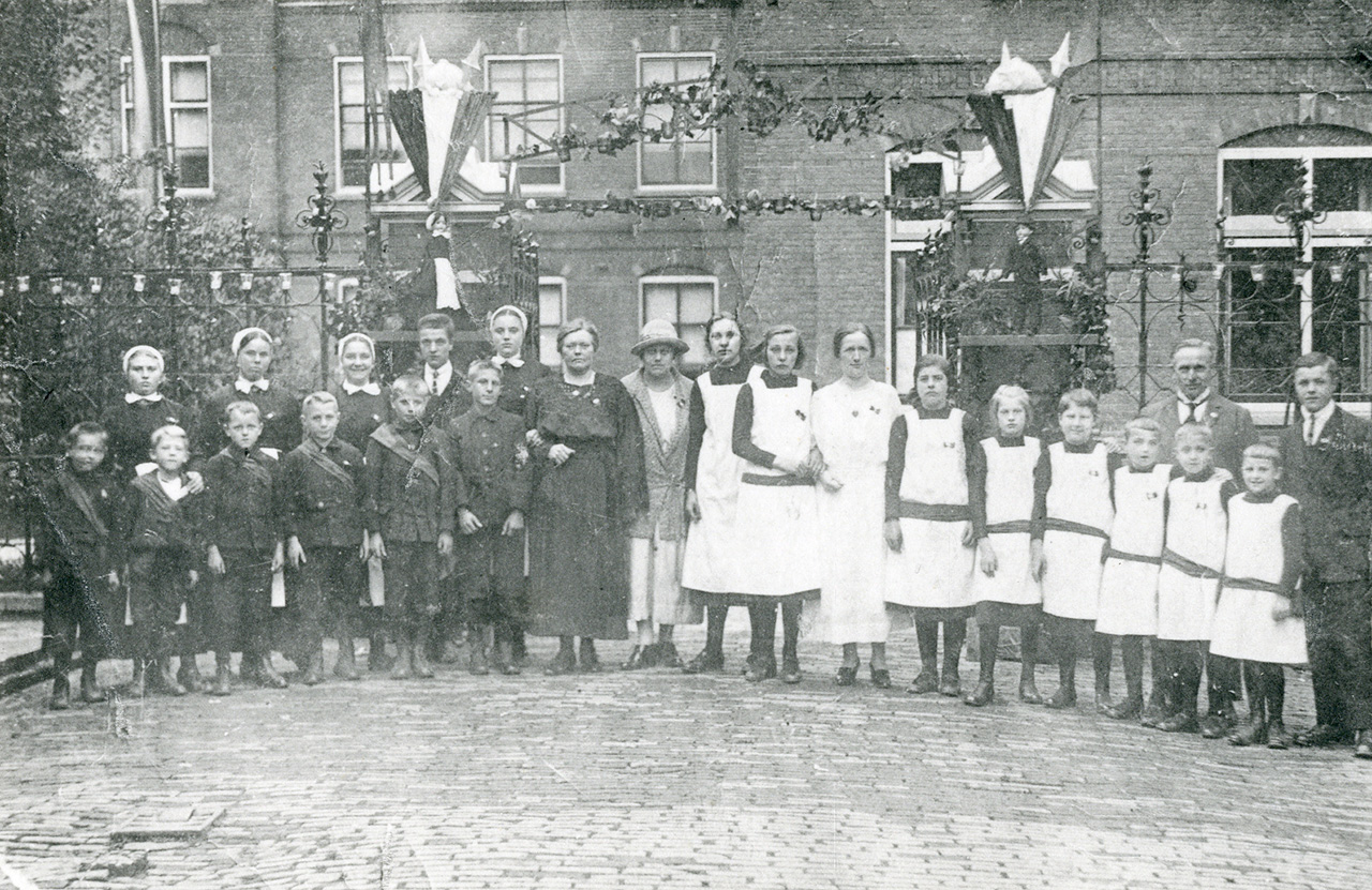 Weeskinderen rond 1923. Martha Broeksma (vrouw in het midden zonder hoed) en haar man Barend Wessemius (2e man van rechts) stonden bekend als 'vader en moeder Wessemius'. Collectie Stadsarchief Vlaardingen, P4466.